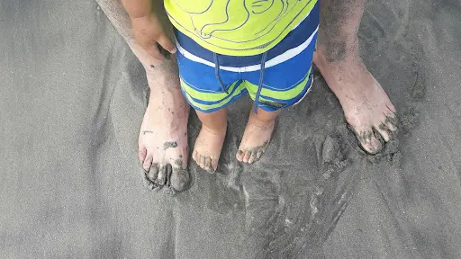 child and adult feet in sand