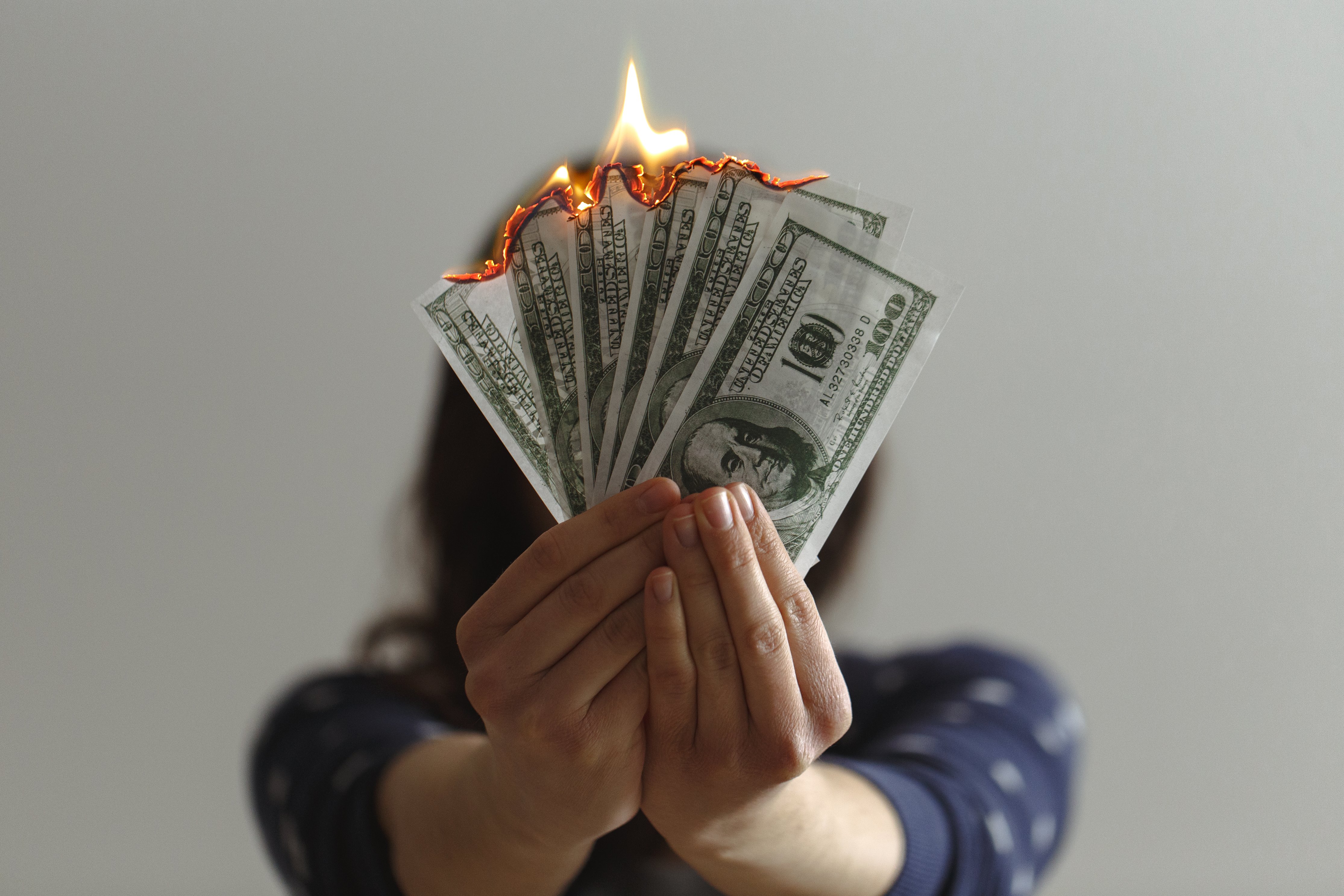 benefits of estate planning - person holding burning currency bills in a fan-like arrangement
