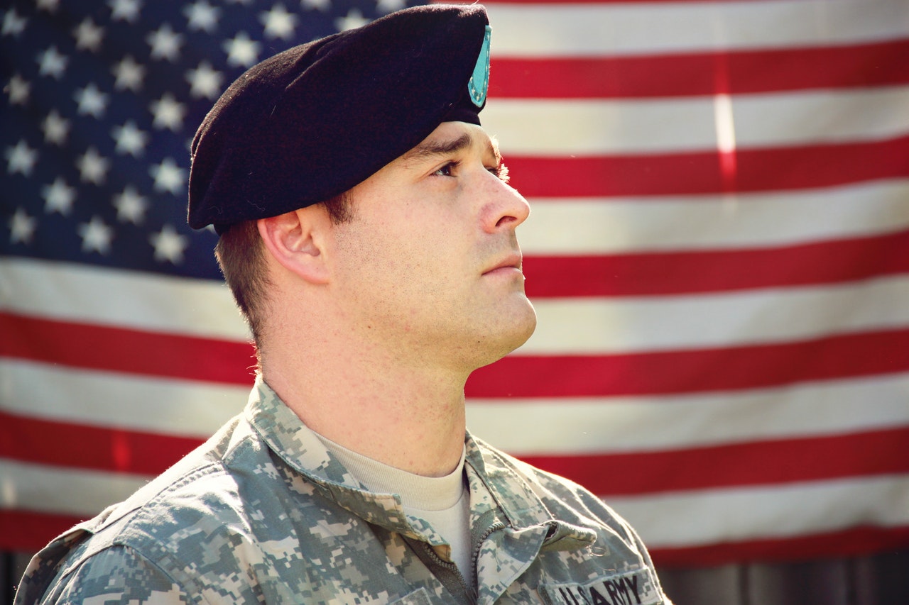 estate planning for military personnel -- US Army man in uniform standing in front of the American flag