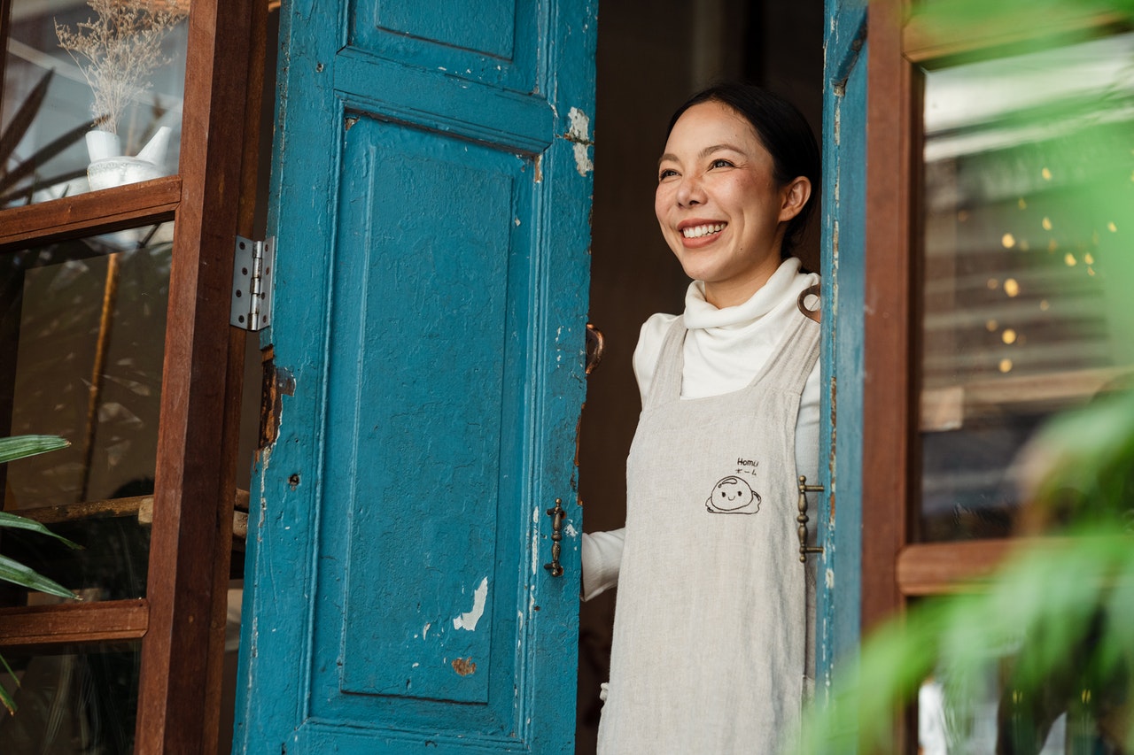 what is a backdoor ira -- Asian woman opening a blue door and smiling