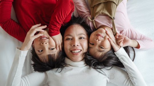 how do I talk to my child about estate planning -- Asian woman lying on bed with two children