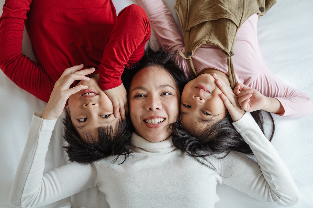 how do I talk to my child about estate planning -- Asian woman lying on bed with two children
