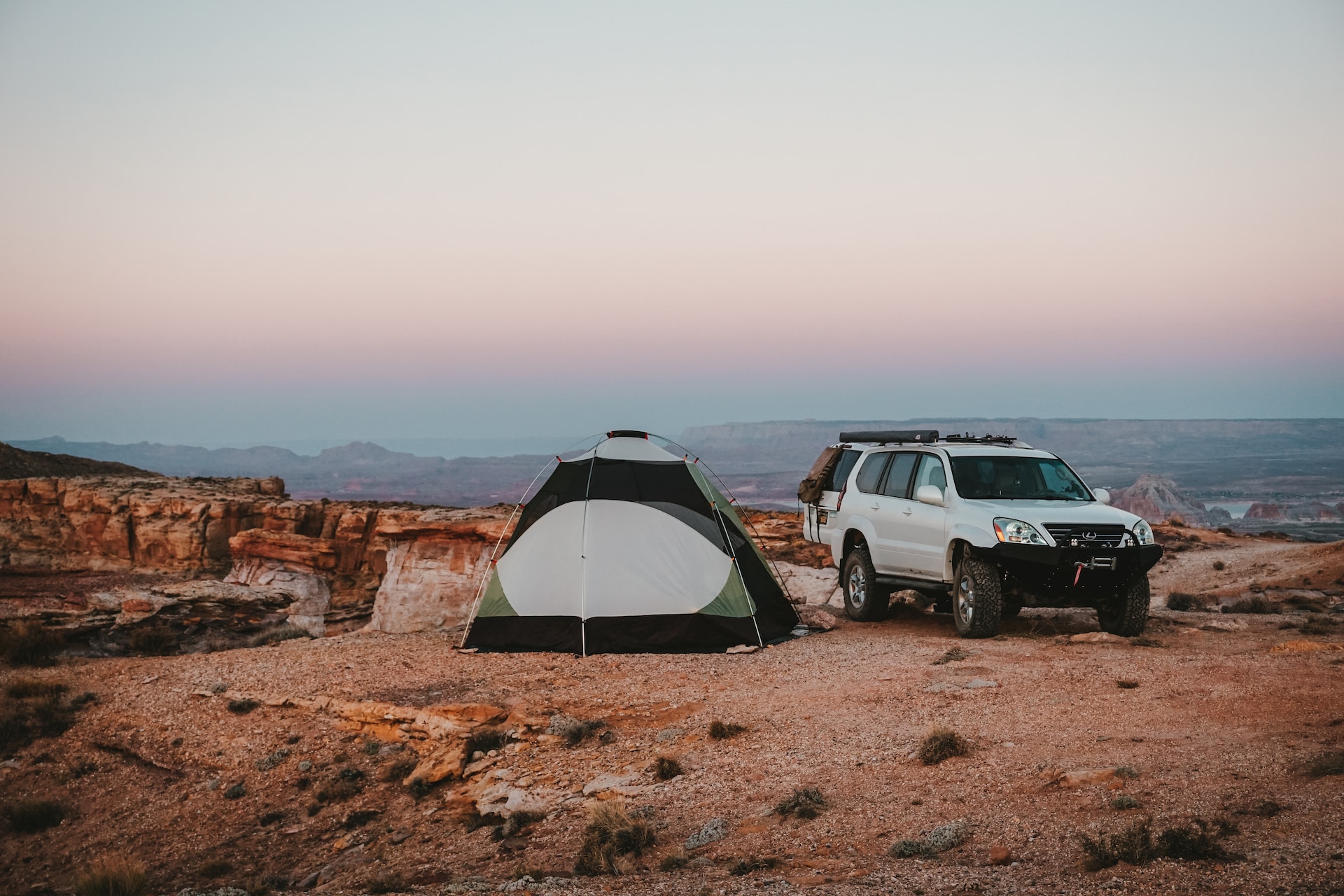 tent and car set up by canyons at sunset