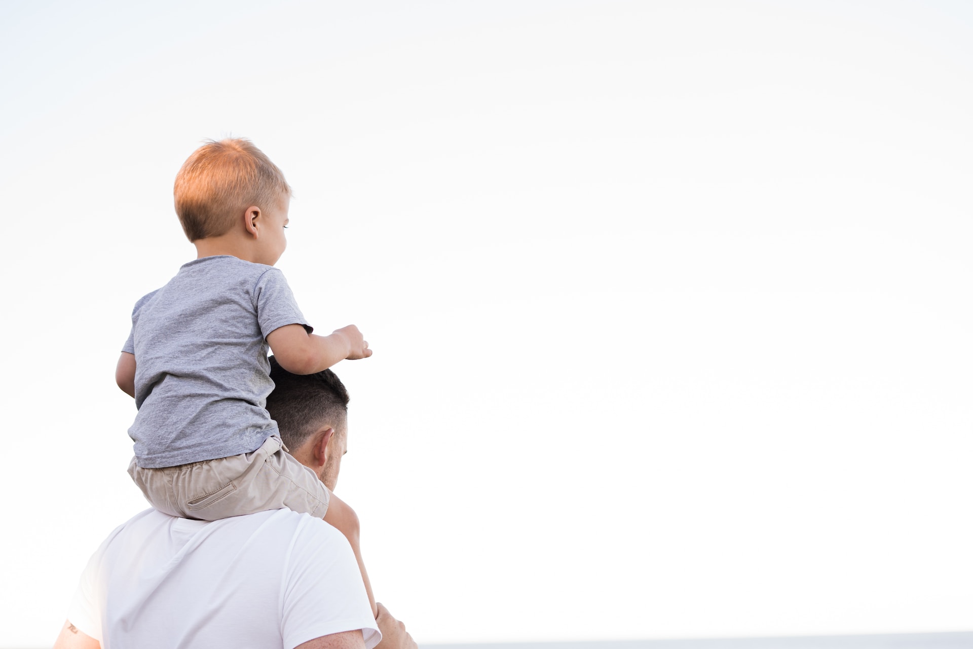 man carrying baby on shoulders white background