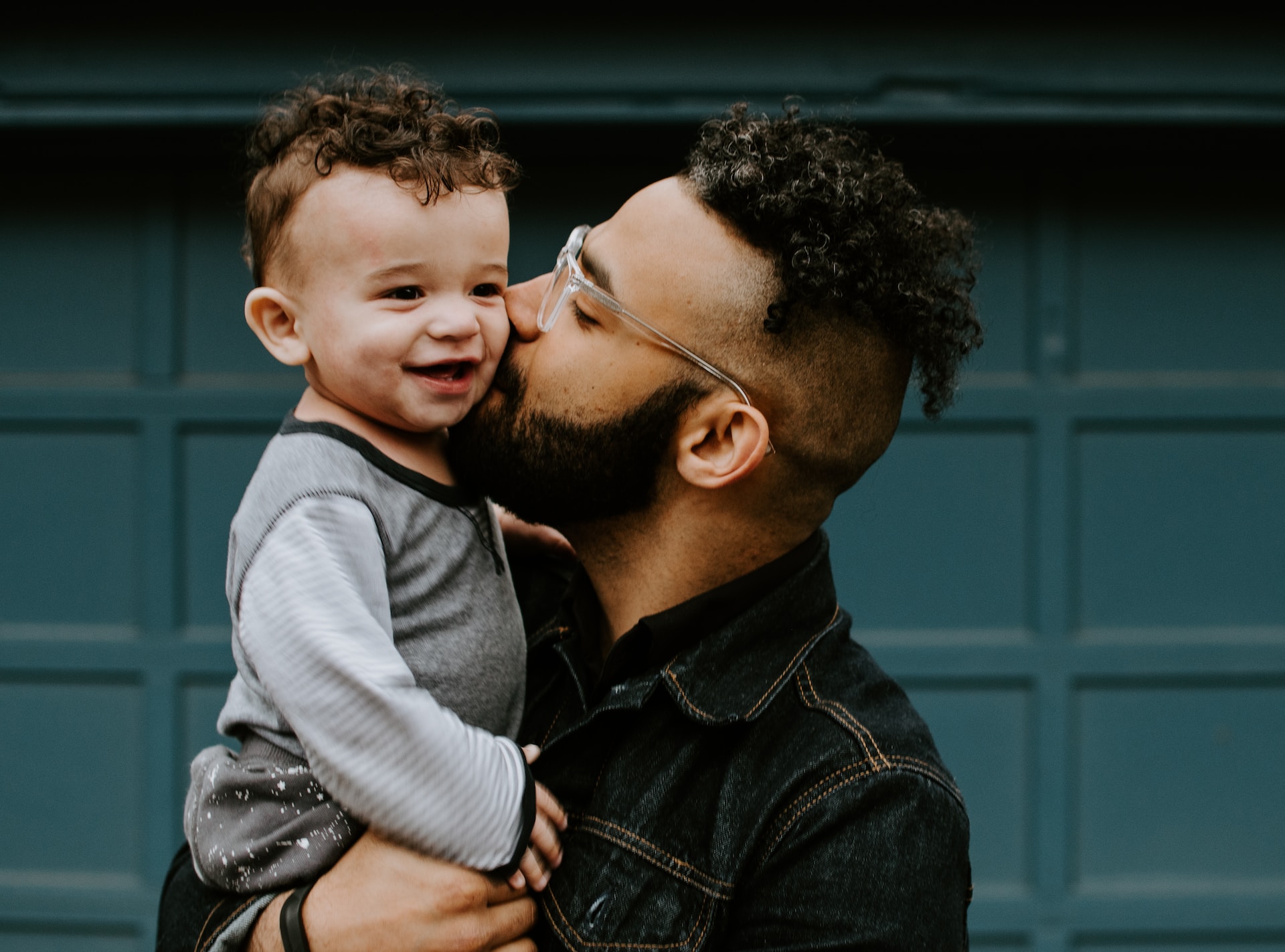 father kissing toddler son on cheek