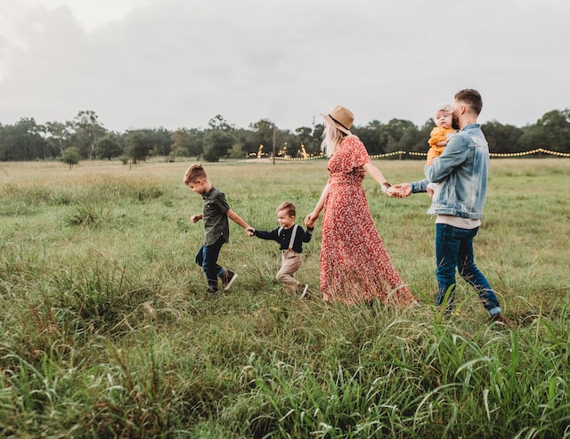 family of five walking through field holding hands