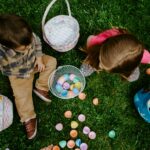 two children sitting in grass counting collected easter eggs